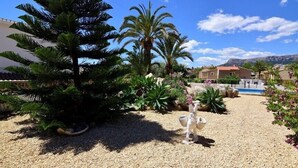 Un jardín con diversas plantas y una estatua decorativa.