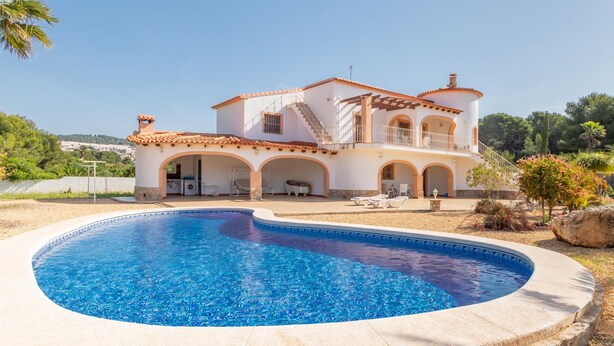 Una villa de estilo mediterráneo con piscina, mobiliario de exterior y jardín.