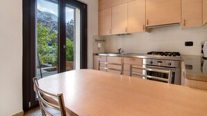 A modern kitchen with a dining table, stainless steel appliances, and a view through the sliding glass door. - Apartment 'Il Nido Del Lago' with Sea View, Wi-Fi and Air Conditioning (Colico Piano)