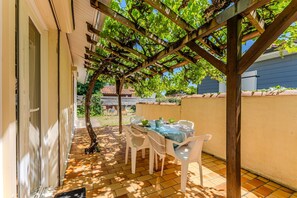 An outdoor patio with a pergola, a table with chairs, and a view of a garden. - Charming 3★ house in Biscarrosse Plage – Shaded terrace, 300m from the ocean (Biscarrosse)