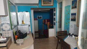 A compact room with a bed, a small table, and a kitchenette area. - Apartment 'I Due Soli' with Sea View, Wi-Fi and Air Conditioning (Santa Cesarea Terme)