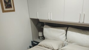 A neatly made bed with pillows and a folded towel, a bedside table with a lamp, and a framed picture on the wall. - Apartment 'I Due Soli' with Sea View, Wi-Fi and Air Conditioning (Santa Cesarea Terme)