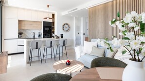 Une cuisine moderne dotée d’un îlot central, de tabourets de bar, d’une table à manger et d’un ventilateur de plafond.