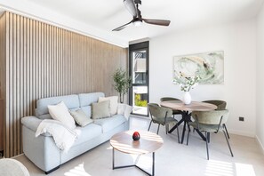 Uma sala de estar moderna com sofá, mesa de centro redonda e área de jantar com cadeiras e mesa.