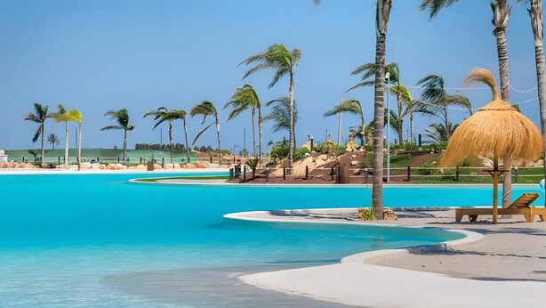 Une piscine à l’eau d’un bleu cristallin, entourée de palmiers et abritée par un parasol en feuilles de palmier.