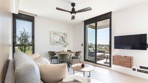 Un salon moderne comprenant un canapé, une table à manger, des chaises, un téléviseur et un balcon avec vue.