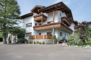 A two-story building with wooden balconies, stone walls, and potted plants.