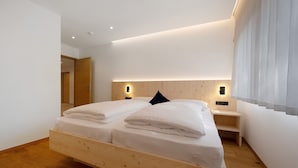 A modern bedroom with a wooden bed, bedside tables, and a nightstand with a lamp. - Holiday Apartment 'Klementhof No. 2' with Mountain View, Shared Pool and Wi-Fi (Naz-Sciaves)