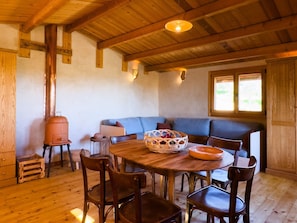 Une pièce chaleureuse avec un plafond en bois, une table ronde en bois et un canapé bleu.