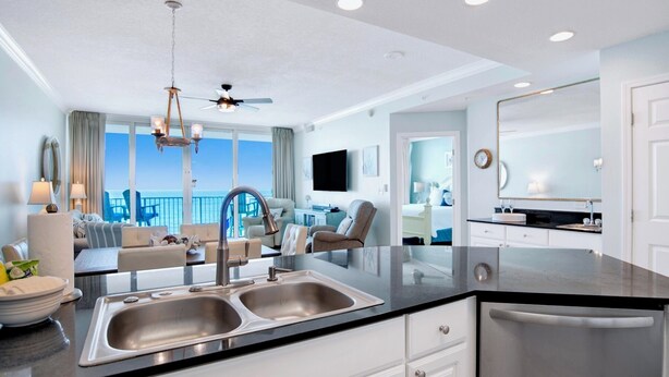 Eine moderne Küche mit einer Spüle, einem Essbereich mit Blick und einem Wohnzimmer mit Deckenventilator.