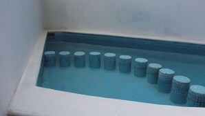 Una piscina con suelo de baldosas y varios objetos cilíndricos alineados.