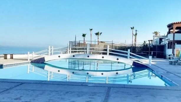 A circular pool with a white railing, surrounded by a concrete deck.