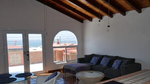 A spacious living area with a balcony, a sofa, a table, and a wicker chair.