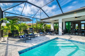 Un espace aménagé au bord de la piscine, avec des chaises longues, des parasols et un barbecue.