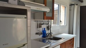A compact kitchen with a built-in refrigerator, a sink, and wooden cabinets.