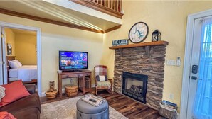 A cozy living room with a stone fireplace, a television, and a comfortable seating area. - 2 Adjacent Houses Rented Together!! (Swanton)