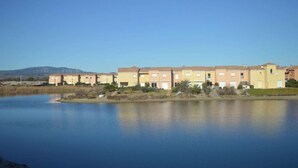 A row of multi-story residential buildings with a body of water in the foreground. - Appart 2 pièces 4 couchages PORT LEUCATE NATURISME (PORT LEUCATE NATURISME)