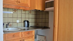 Eine Küche mit Holzausstattung, einer Mikrowelle, einem Toaster und einem Wasserkocher auf der Arbeitsfläche.