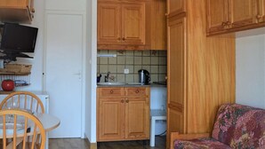Eine kleine Küche mit Holzausstattung, gefliestem Rücksprung und einem Essbereich mit Stuhl und Tisch.