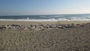 A beach with a rocky shoreline and waves in the background. - Appart Studio / mezz 2 couchages PORT LEUCATE NATURISME (PORT LEUCATE NATURISME)