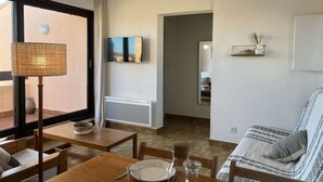Ein Essbereich mit einem Holztisch, Stühlen, einer Lampe und einem an der Wand befestigten Fernseher.