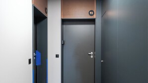 Moderni hissi, jossa on metallinhohtoinen pinta, kahvallinen ovi ja pieni ohjauspaneeli seinässä.