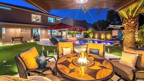 Un patio al aire libre con piscina, sillones de descanso y una fogata.