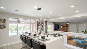 Una cocina moderna con una isla central, asientos tipo barra y grandes ventanales con vistas al exterior.