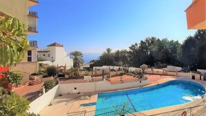 A swimming pool with a curved design, surrounded by a fenced area and potted plants. - Ref: 263 Apartment with sea views on second line beach in Torreblanca (Fuengirola)