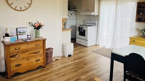Una cocina acogedora con armarios de madera, una estufa blanca y una zona de comedor con mesa y sillas.