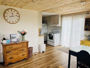 A cozy kitchen with wooden cabinets, a white stove, and a dining area with a table and chairs.