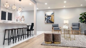 Una cucina moderna con sgabelli da bar, un'area pranzo con sedie, un tappeto e un grande quadro astratto.