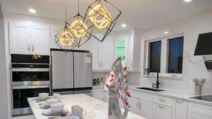 Una cucina moderna con mobili bianchi, un'isola centrale con una scultura decorativa e un forno integrato.