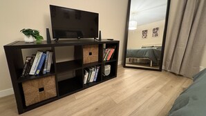 Una sala moderna con un mueble de entretenimiento negro, un televisor y una estantería.