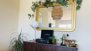 Una habitación con un mueble de madera oscura, un espejo con marco dorado y una lámpara colgante de ratán.