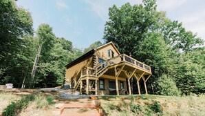 Una baita di legno con un portico, immersa tra gli alberi.