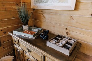 A wooden cabin interior with a wooden cabinet, a framed map, a potted plant, a small trash bin, and a candle holder. - Cozy 2BR with AMAZING views in Buck Mountain (Purlear)