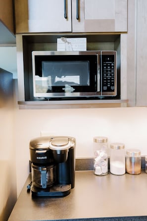 A kitchen with a coffee maker, a microwave, and a coffee pod holder.
