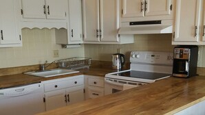 A kitchen with white cabinets, a wooden countertop, a stove, and three wooden stools.