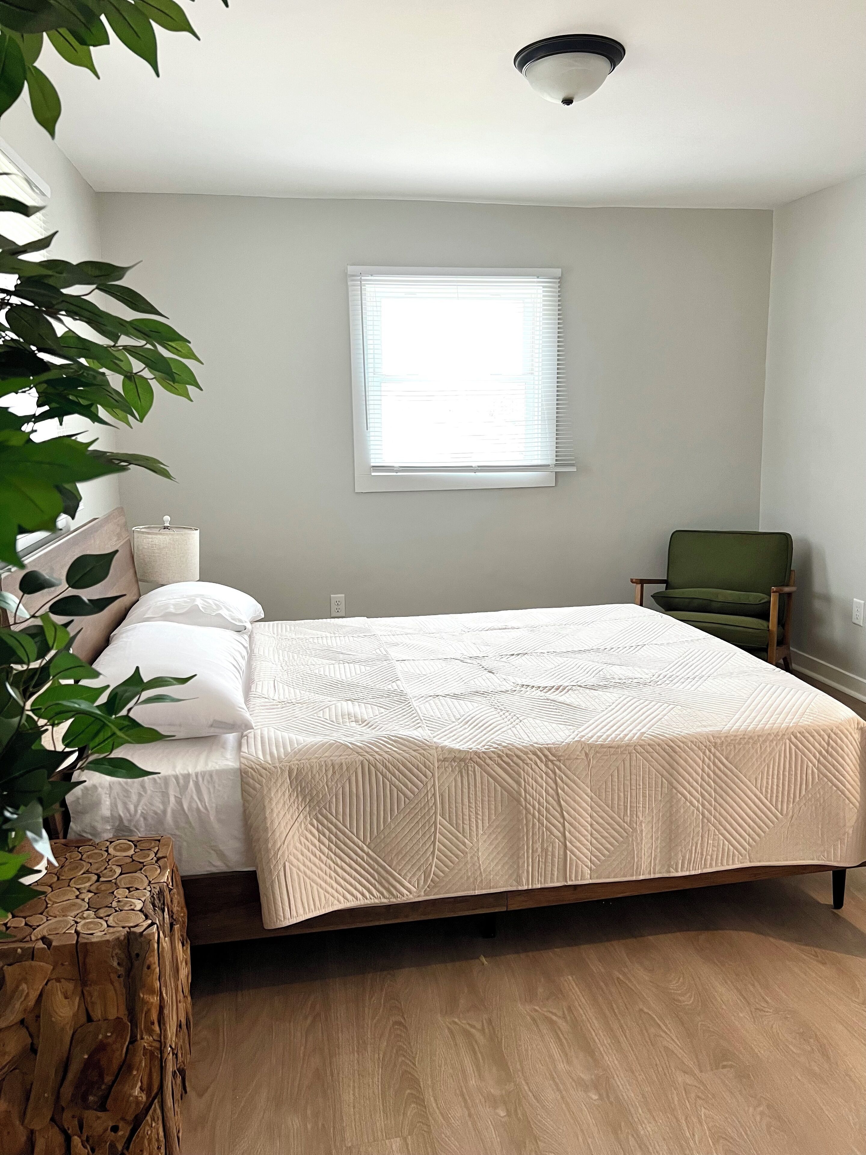 Une chambre à coucher avec un lit, une fenêtre, une chaise et une plante.