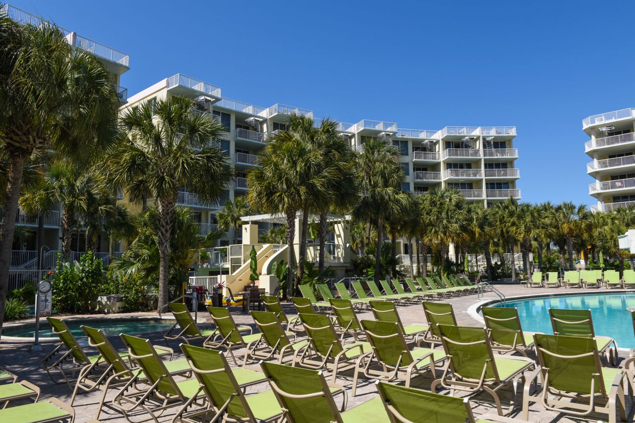 A hotel pool area with multiple lounge chairs and a clear blue sky.