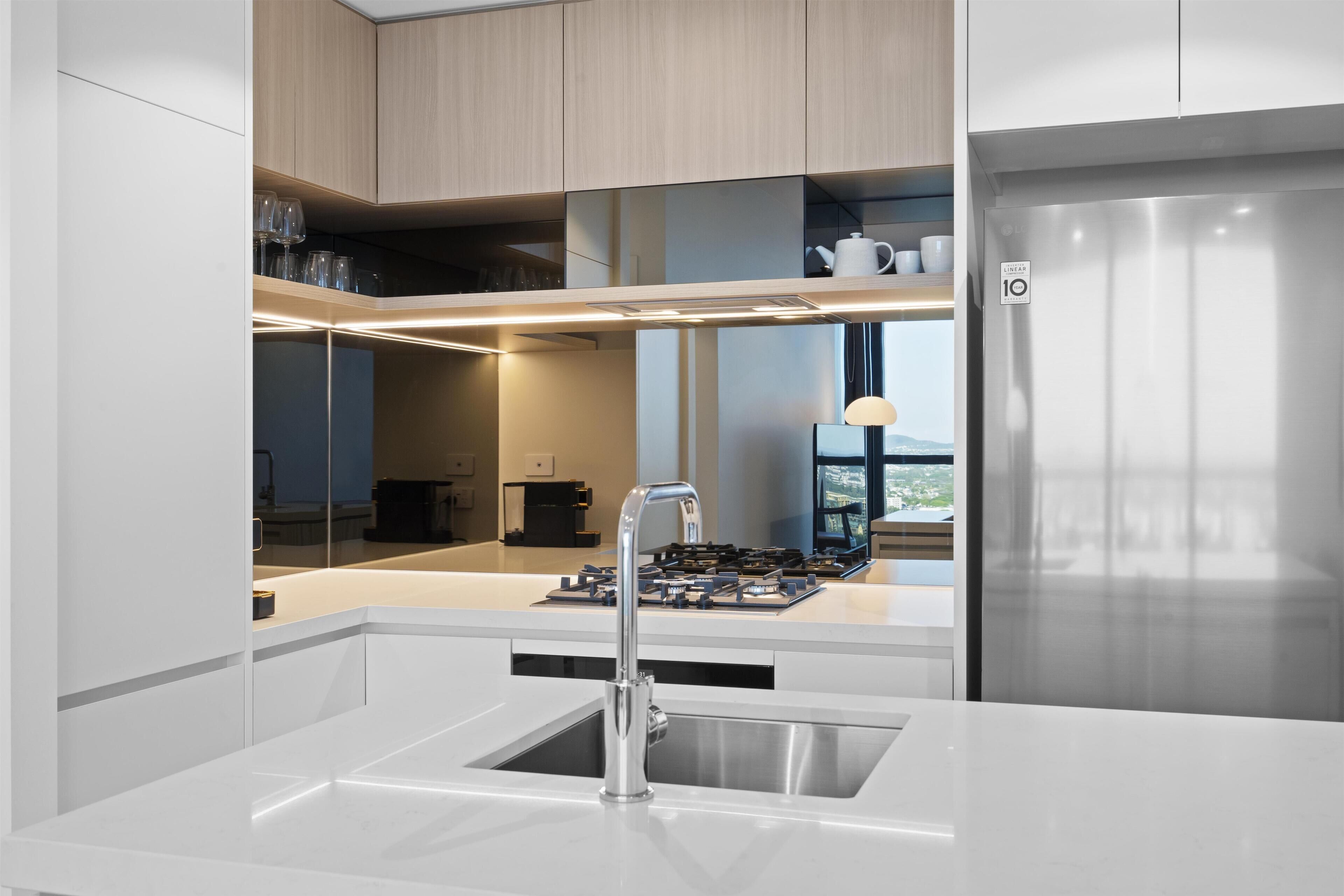 Una cocina moderna con un refrigerador de acero inoxidable, una estufa a gas empotrada y una encimera blanca.