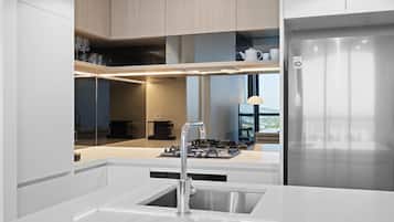 A modern kitchen with a stainless steel refrigerator, a built-in gas stove, and a white countertop.
