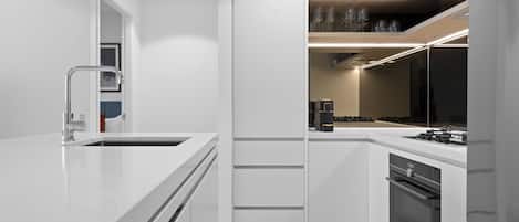 Una cocina moderna con armarios blancos, un refrigerador de acero inoxidable y un horno empotrado.