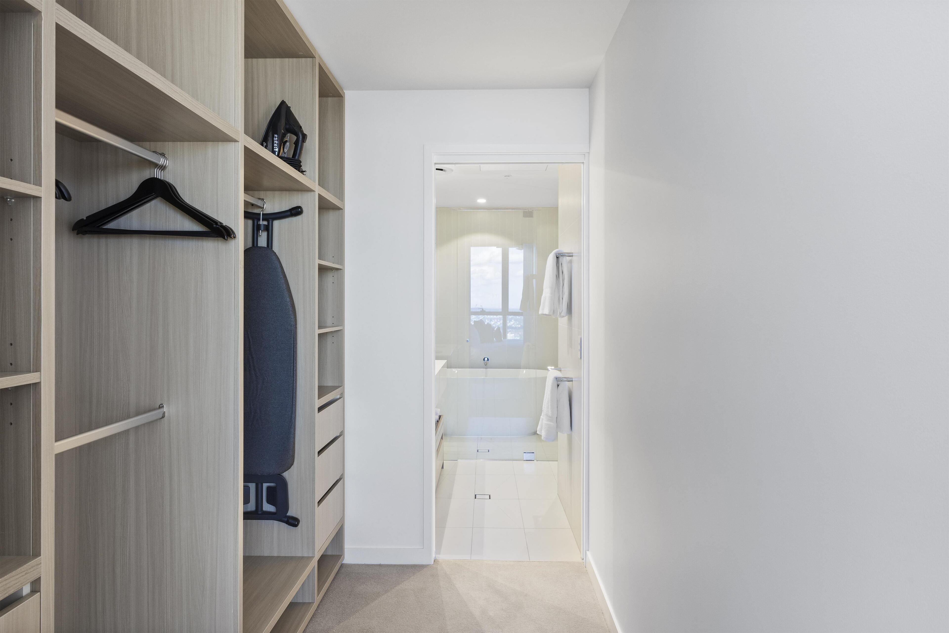 A walk-in closet with wooden shelves and a hanging rack.
