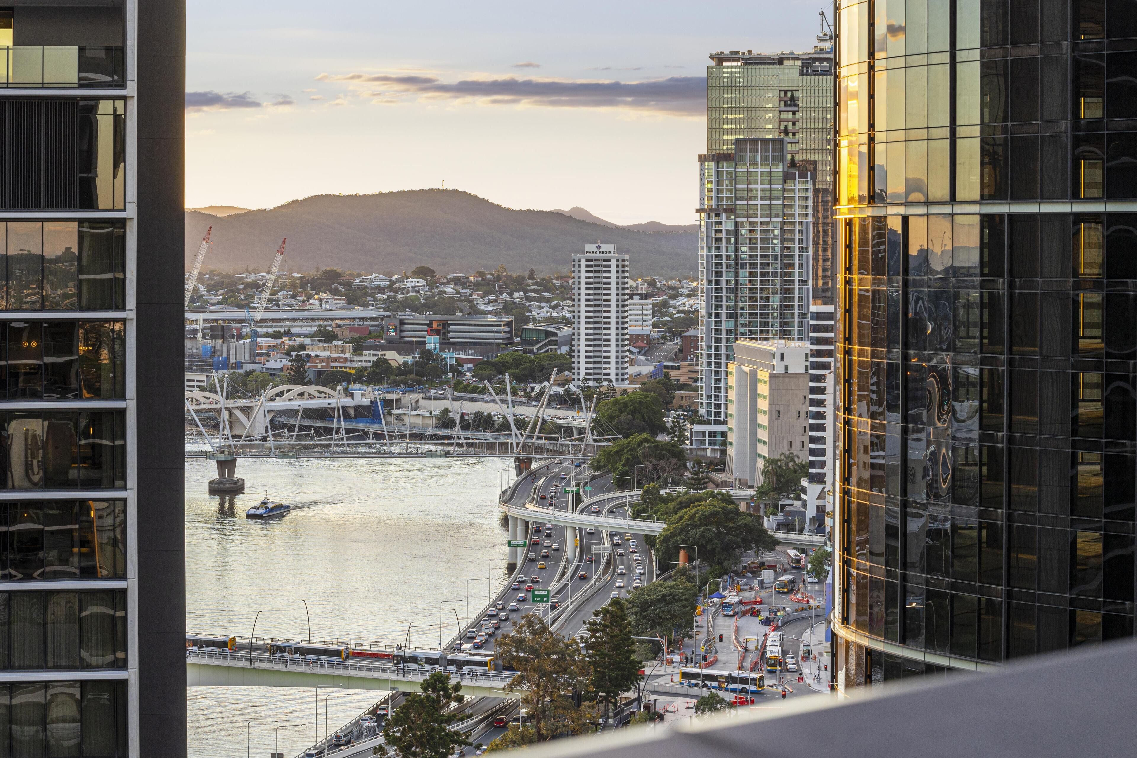 A high-rise building with a view of a river and a bridge in the background.