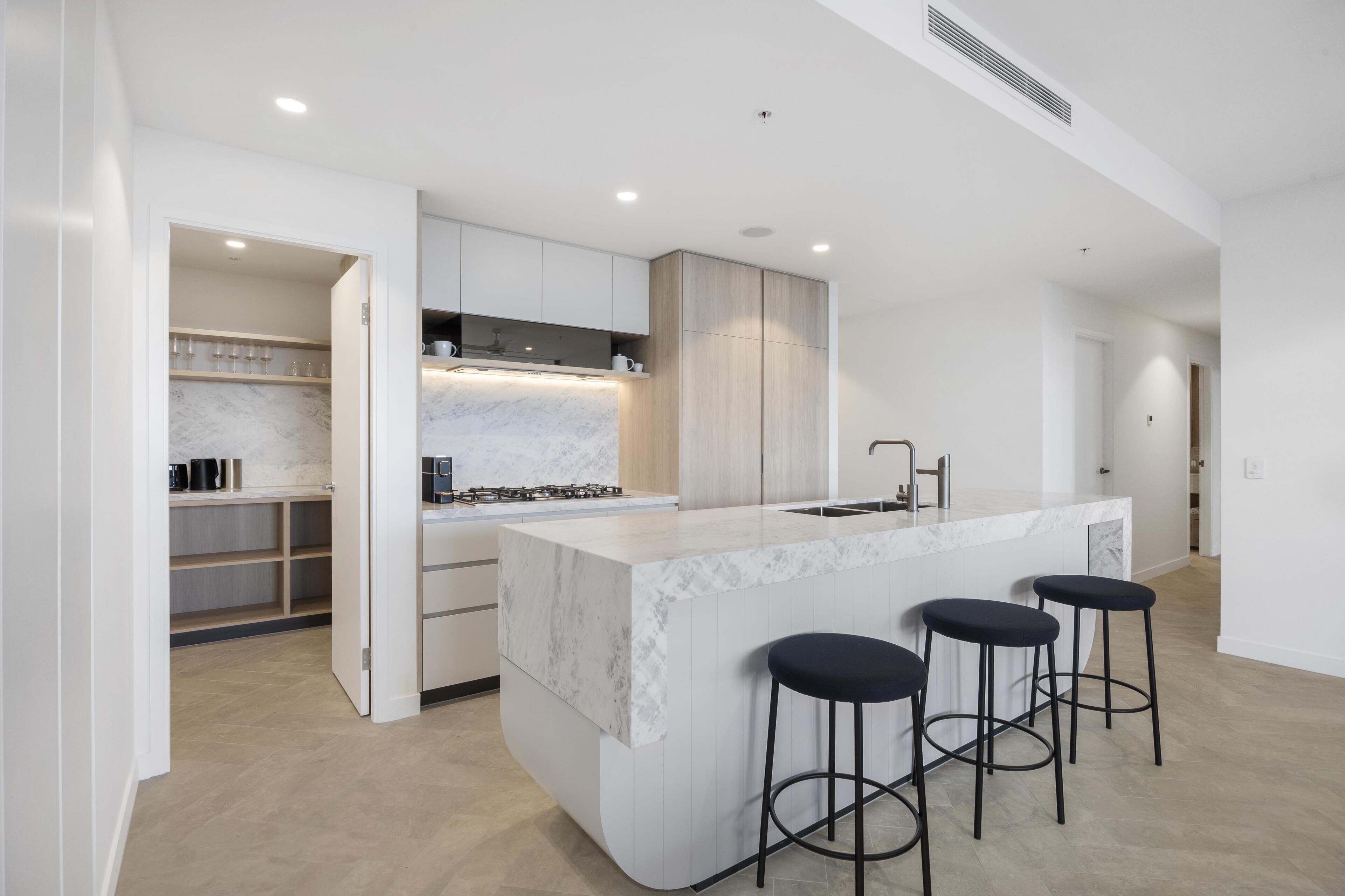 Una cocina moderna con encimera de mármol, armarios de madera y una isla integrada con taburetes de bar.