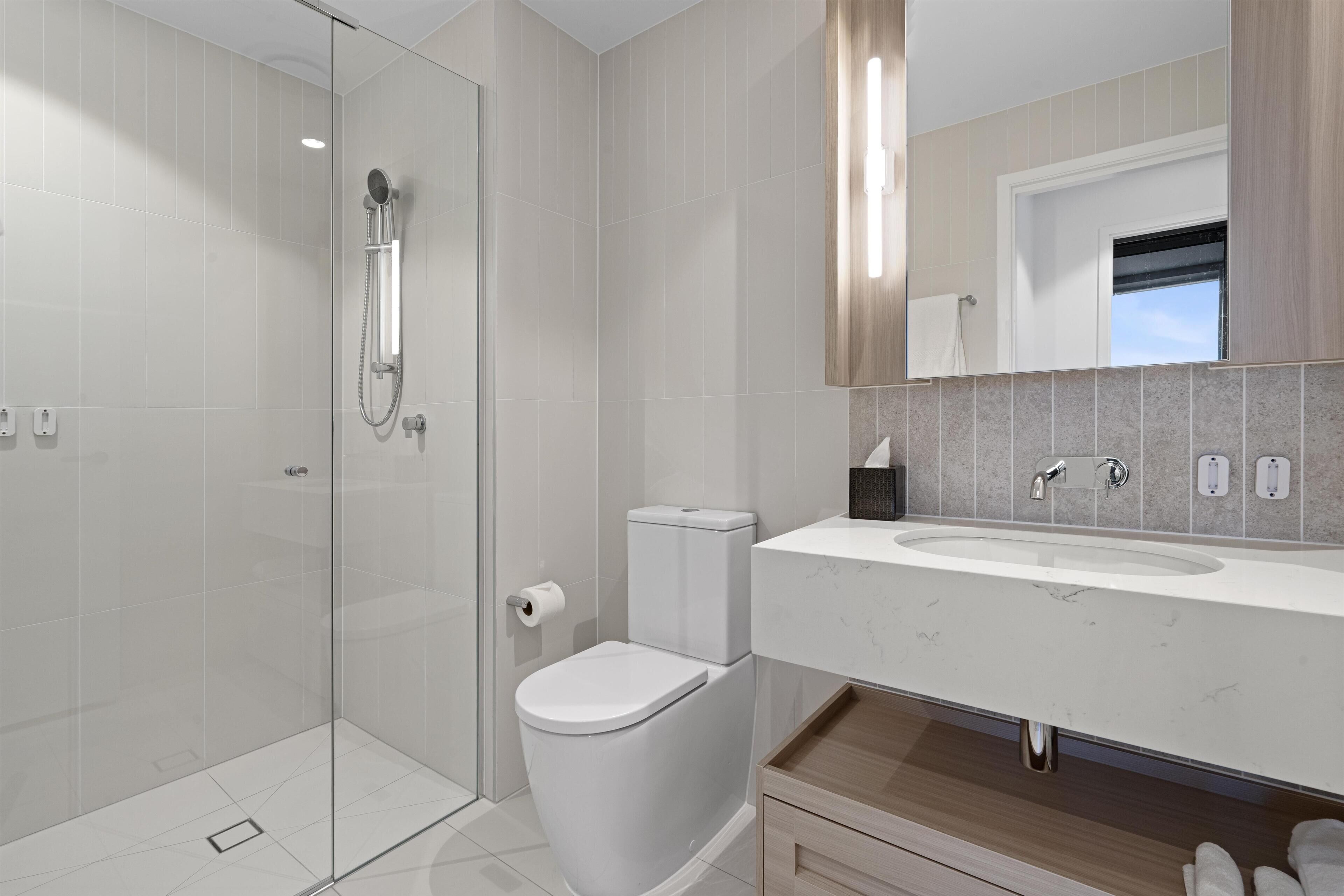 A modern bathroom with a glass-enclosed shower, a toilet, and a vanity with a sink.