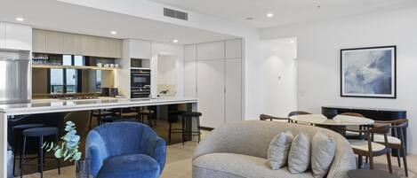 A modern kitchen with a central island, a dining area with a table and chairs, and a living area with a sofa and a coffee table.
