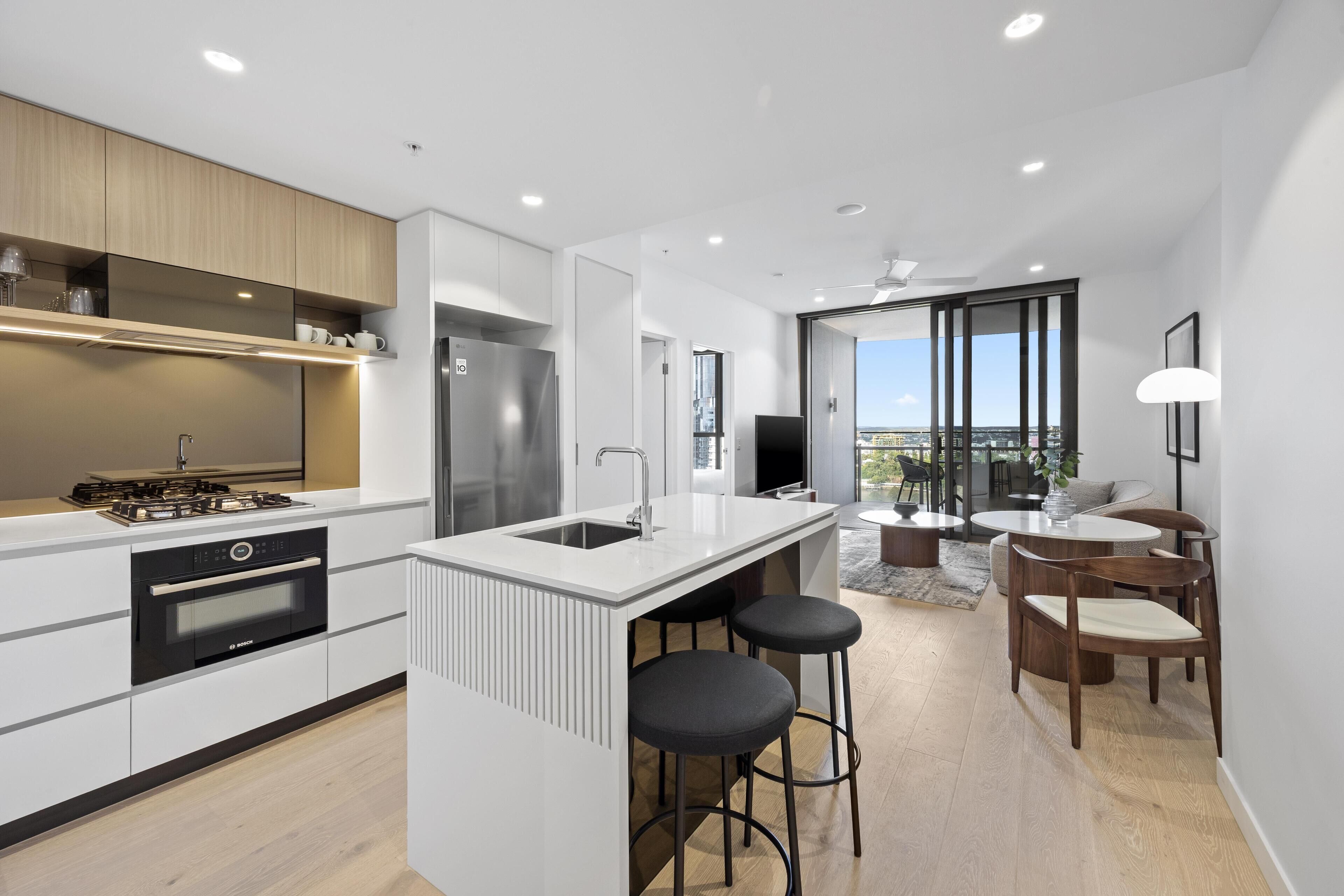 A modern kitchen with a central island, built-in oven, and stainless steel appliances.